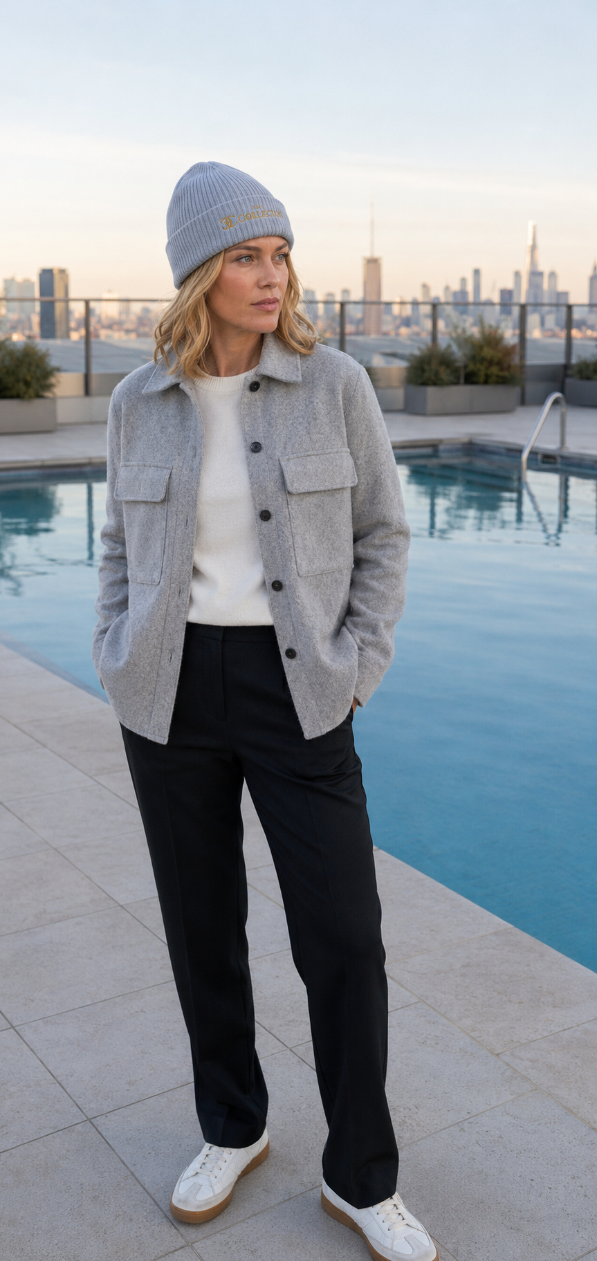 Model wearing The Collection Cuffed Beanie Gold Logo Knit Hat by rooftop pool